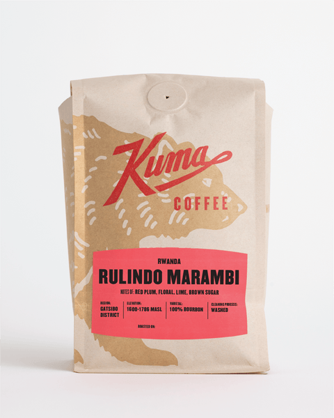 A stand-up coffee bag from Kuma Coffee on a clean white background. The packaging is a kraft paper pouch with a large red script logo reading 'Kuma' and 'COFFEE,' plus a coral-red label at the bottom that reads 'RWANDA RULINDO MARAMBI.