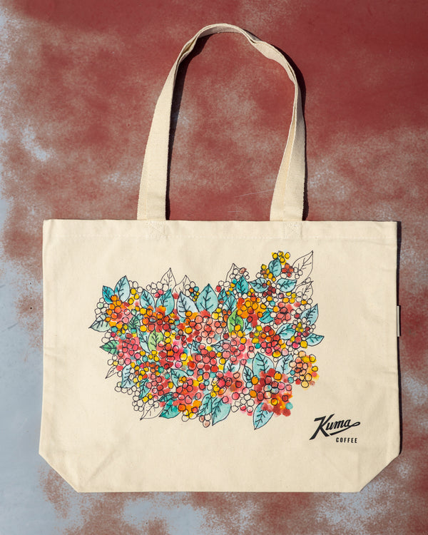 Beige tote bag with floral design and 'Karma Coffee' branding on a textured background