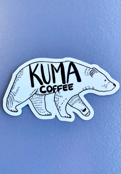 dye cut sticker of an illustration of a walking bear with the text kuma coffee written on it, blue background